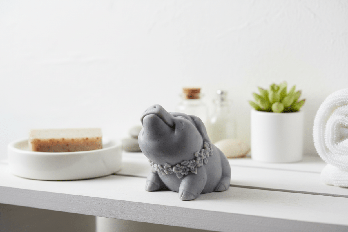 Gray elephant figurine with a floral headband on a white surface with bathroom items in the background.
