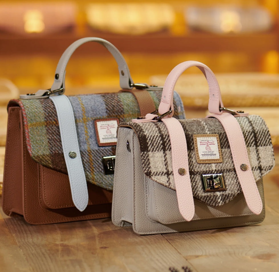 Two handbags with plaid patterns and leather straps on a wooden surface.