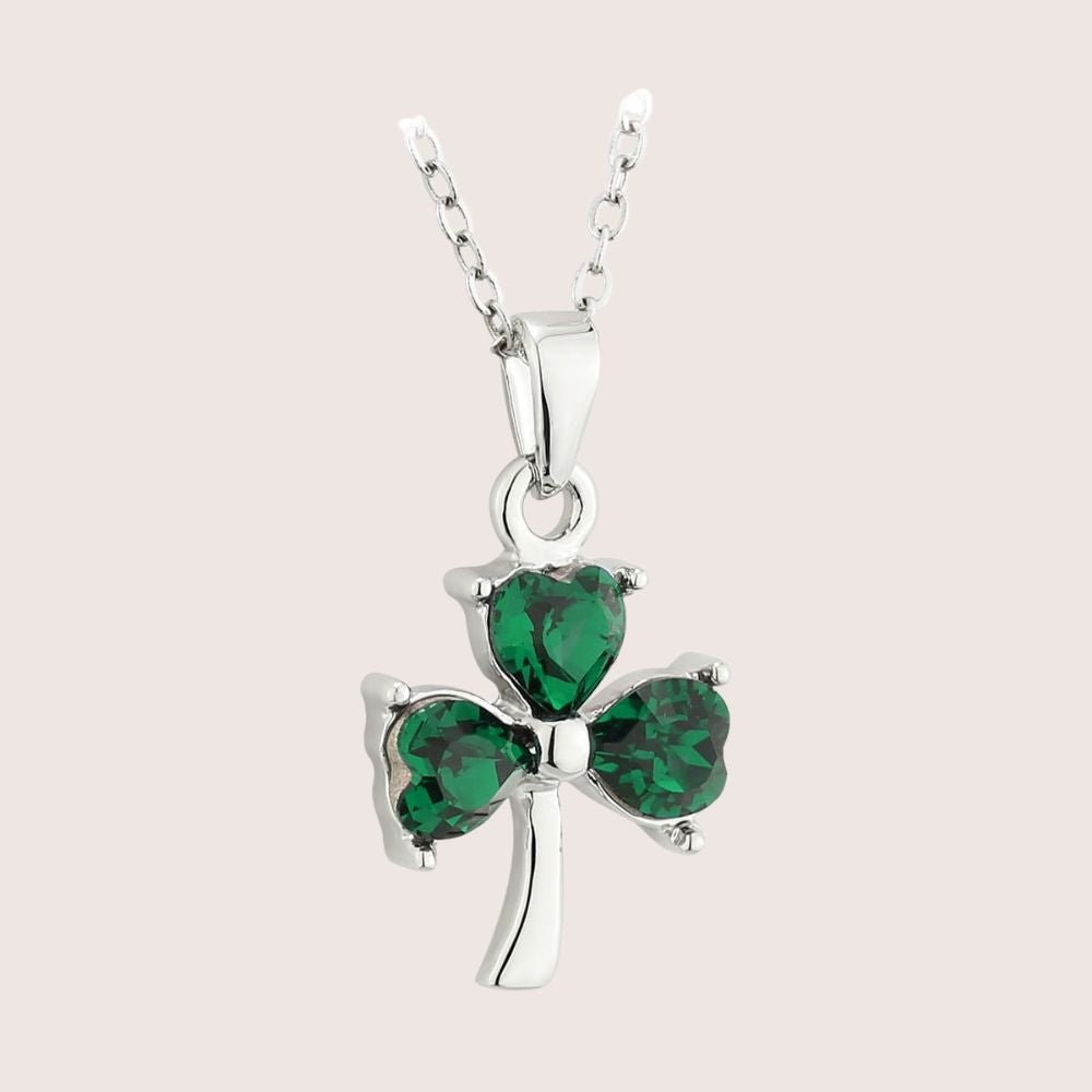 Silver necklace with a green shamrock pendant on a light pink background